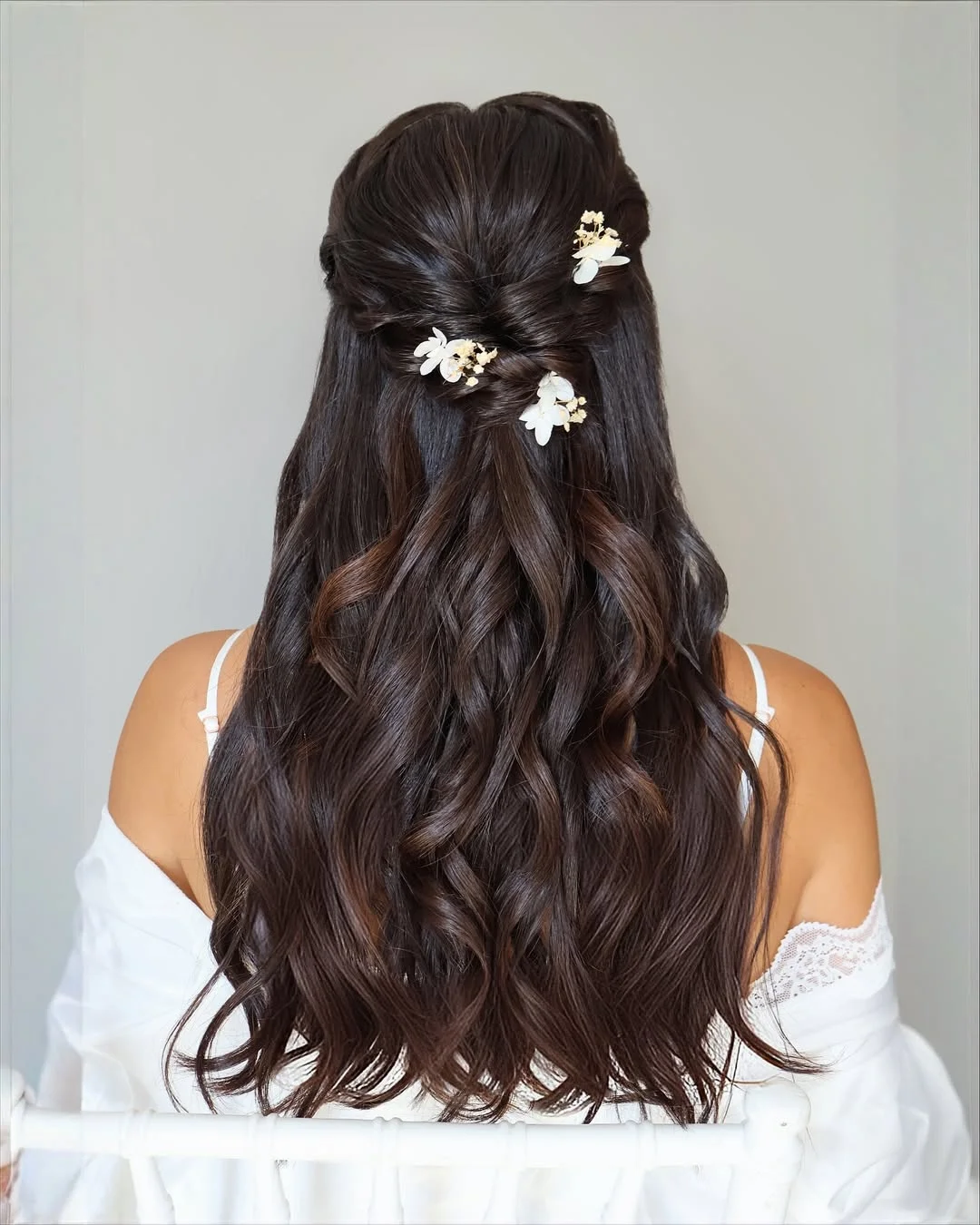 boho summer wavy hairstyle 2026 Deep Brunette Waves with Soft Floral Half Up Accent