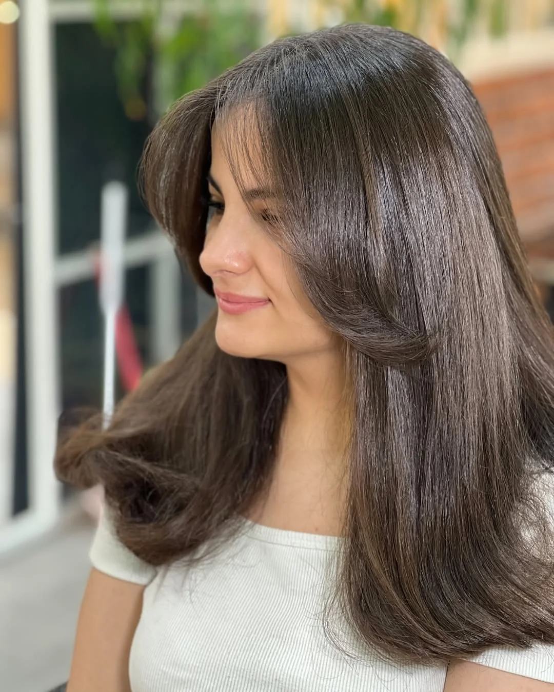 salon summer haircuts with bangs 2026 Glass Brunette Blowout With Sculpted Curtain Layers